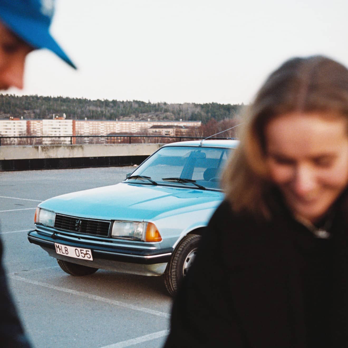 Bil på parkering med två personer i förgrunden